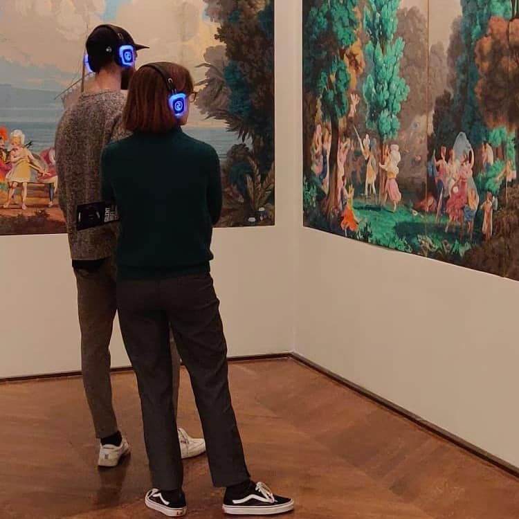 Palazzo del Louvre Bezoekers met draadloze koptelefoons voor schilderijen in het Louvre
