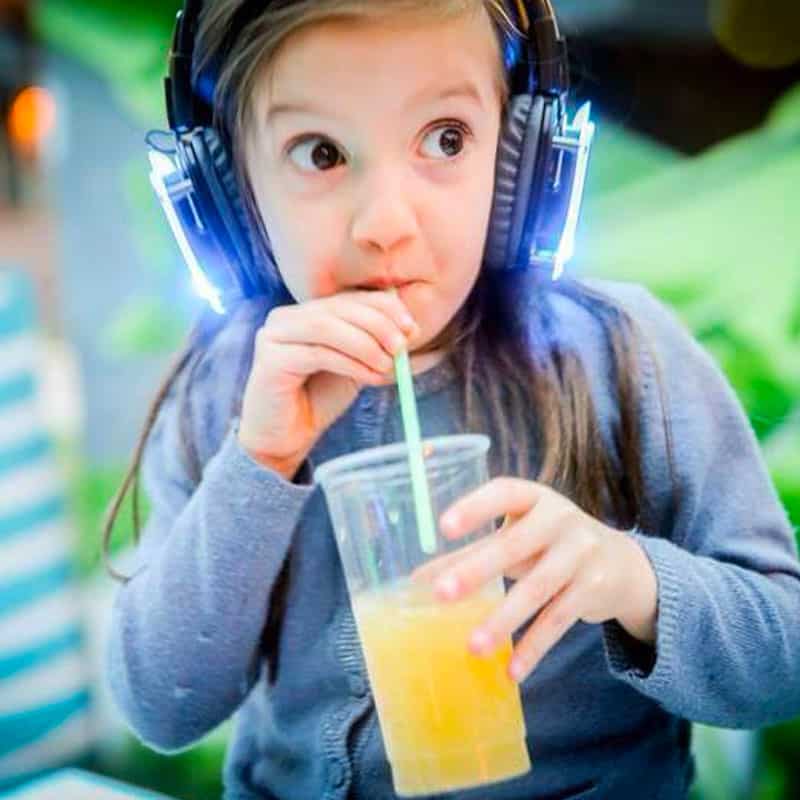 discotecabambini Meisje met blauwe led-koptelefoon drinkt uit een beker op een feest