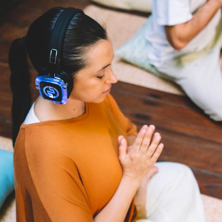 newyogi Mediterende vrouw met draadloze koptelefoon tijdens een Silent Yoga-les