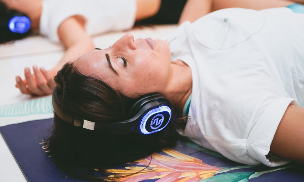 Meditazione con cuffie Liggende vrouw met draadloze koptelefoon tijdens een begeleide meditatie